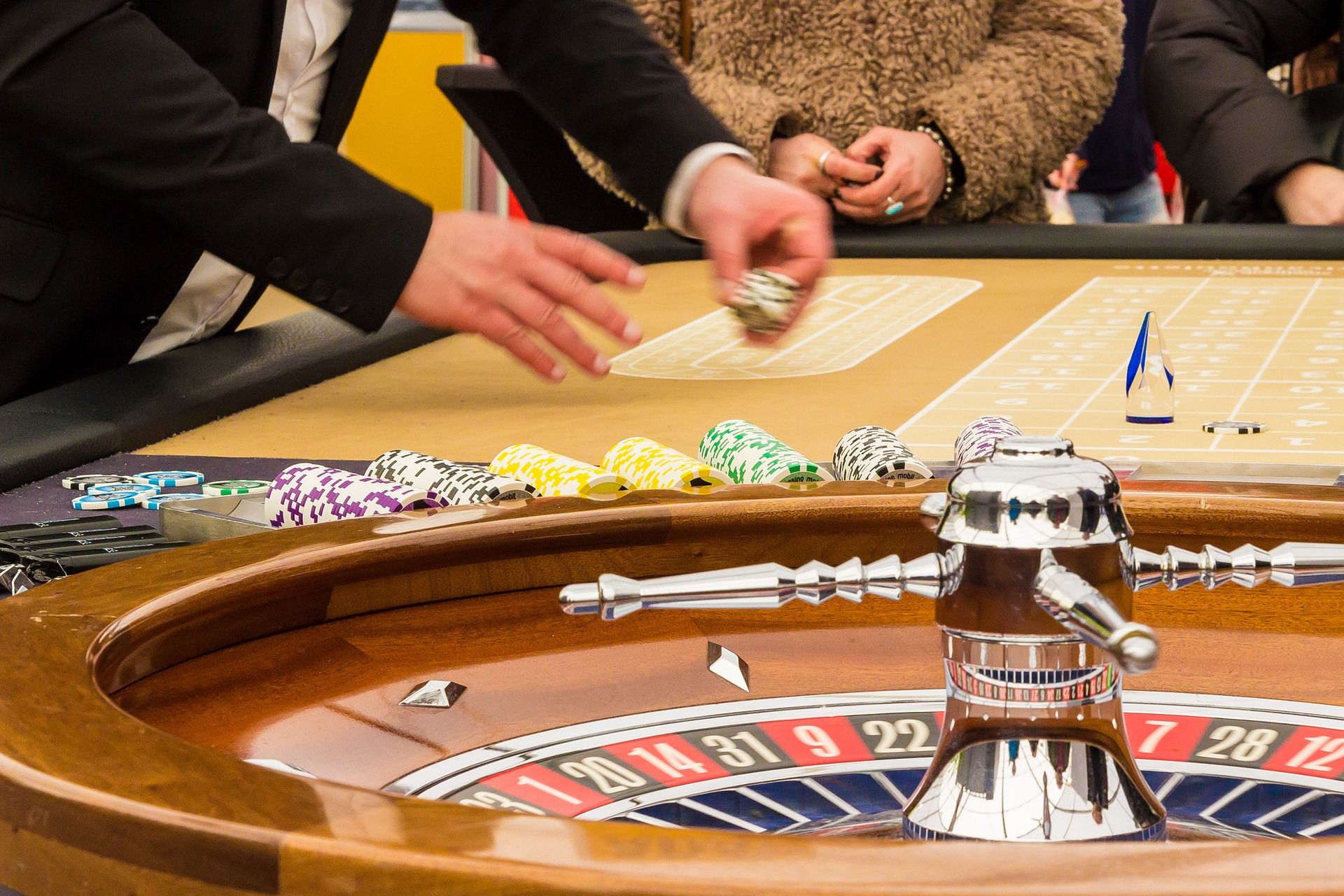 Ein Roulettekessel aus Holz mit Händen von Spielern