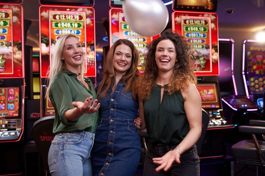 Drei Frauen vor den Spielautomaten lachend in de Kamera schauend in der Spielbank Leipzig