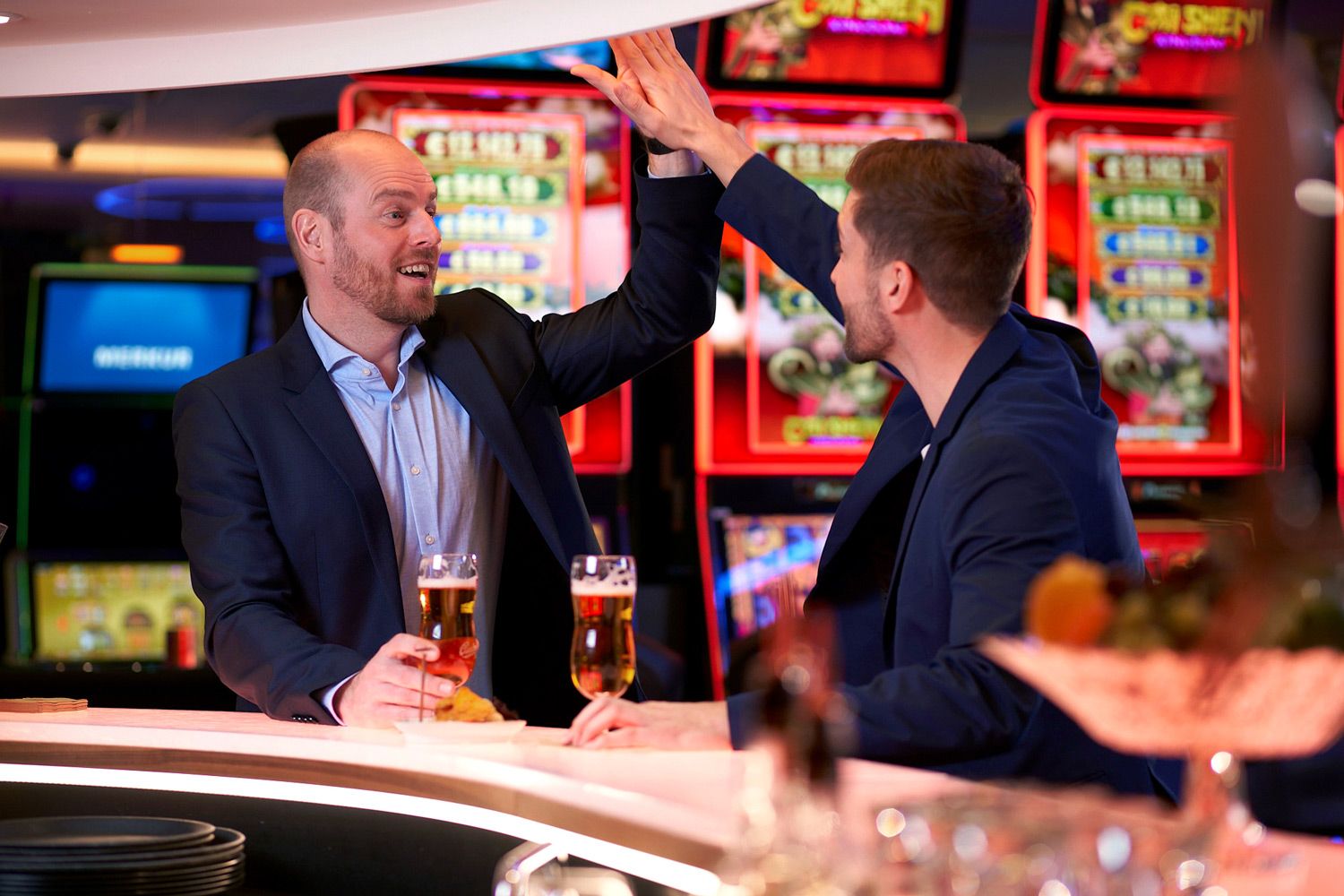 Two men shake hands over a beer at the bar.
